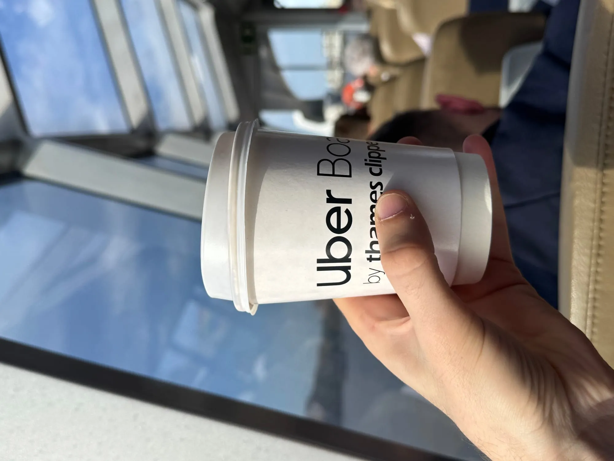 Me holding a hot chocolate on an Uber boat