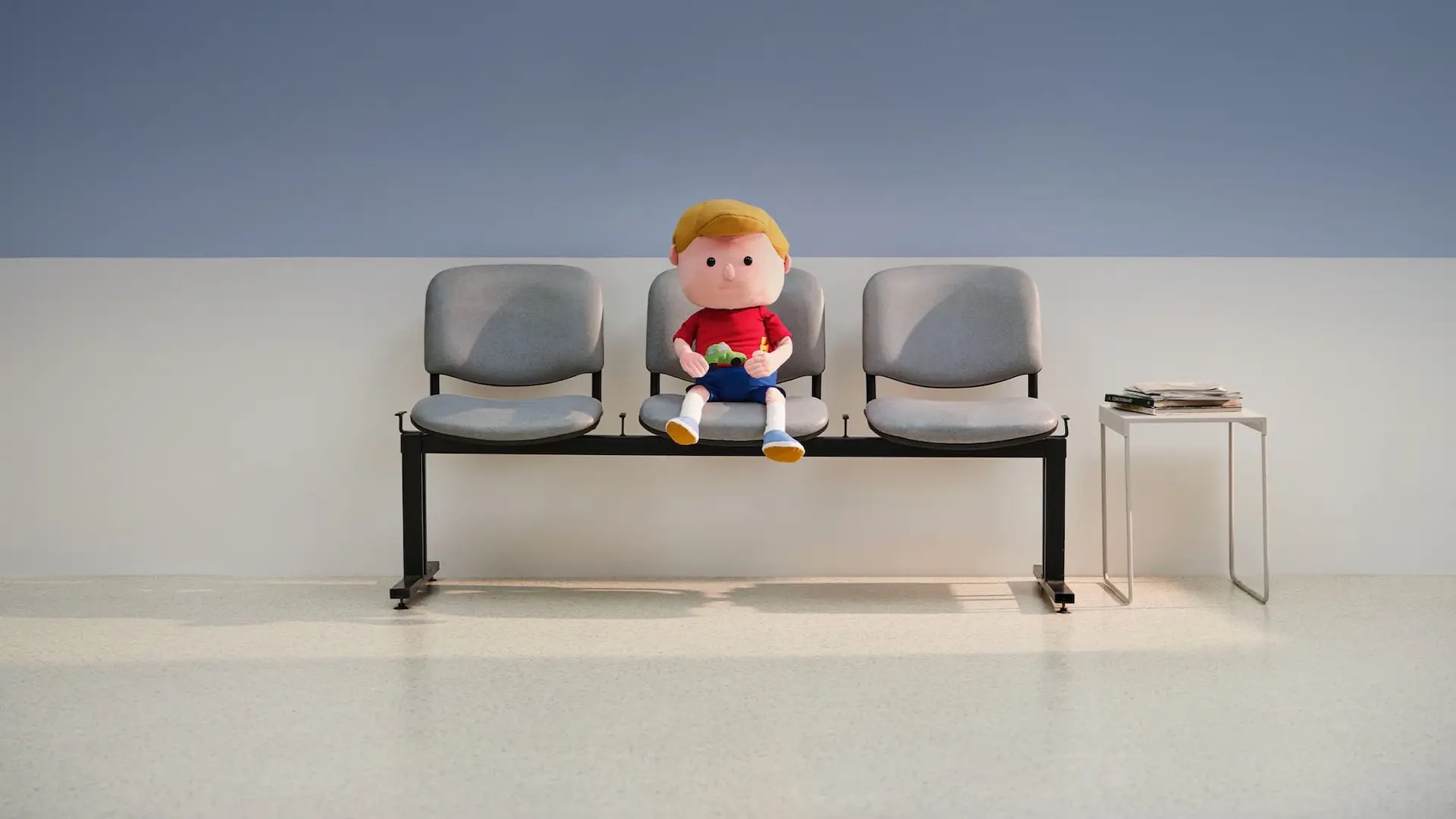 The doll of Ralph sitting on a bench, waiting.